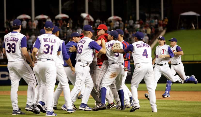 Texas Rangers players restrain Los Angeles Angels' John Lackey , center in red, during a...