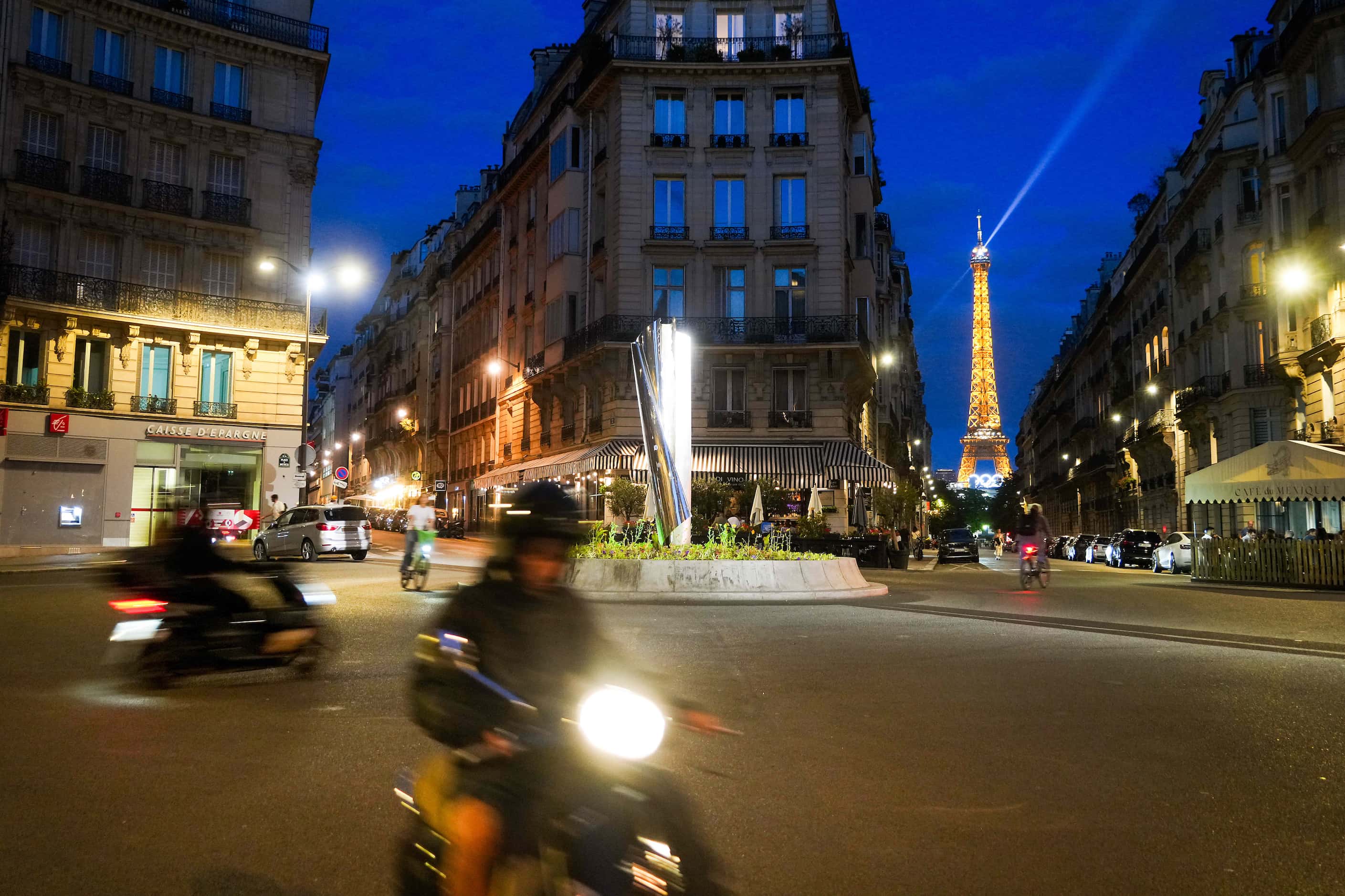 The Eiffel Tower is seen lighted with the Olympic rings as traffic circles through La Place...