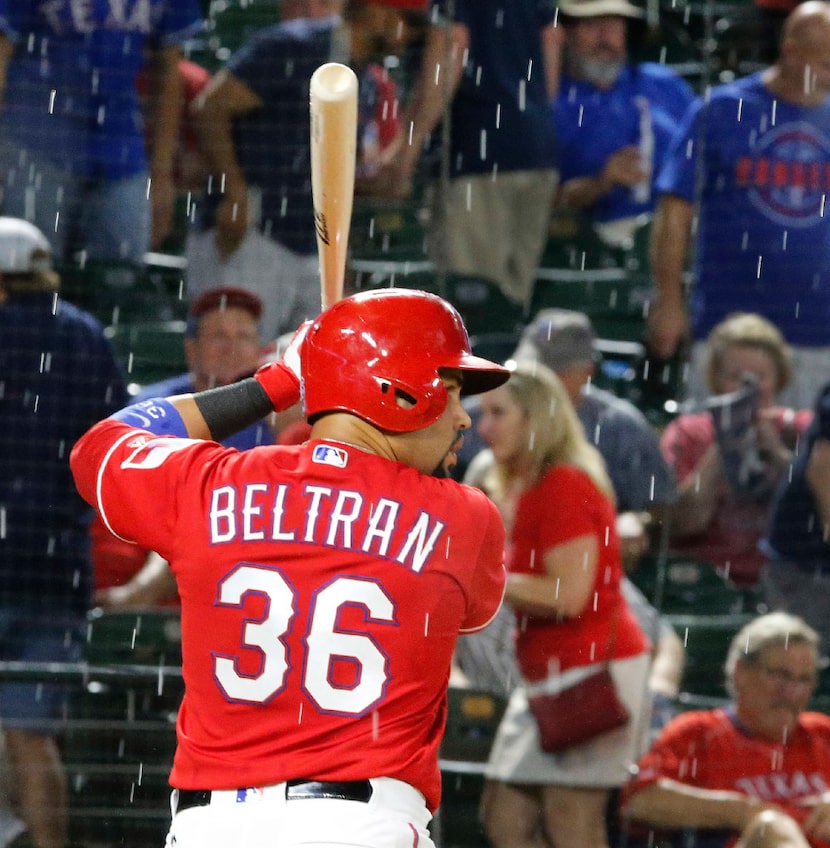 Texas Rangers designated hitter Carlos Beltran (36) tries to concentrate as the rain comes...