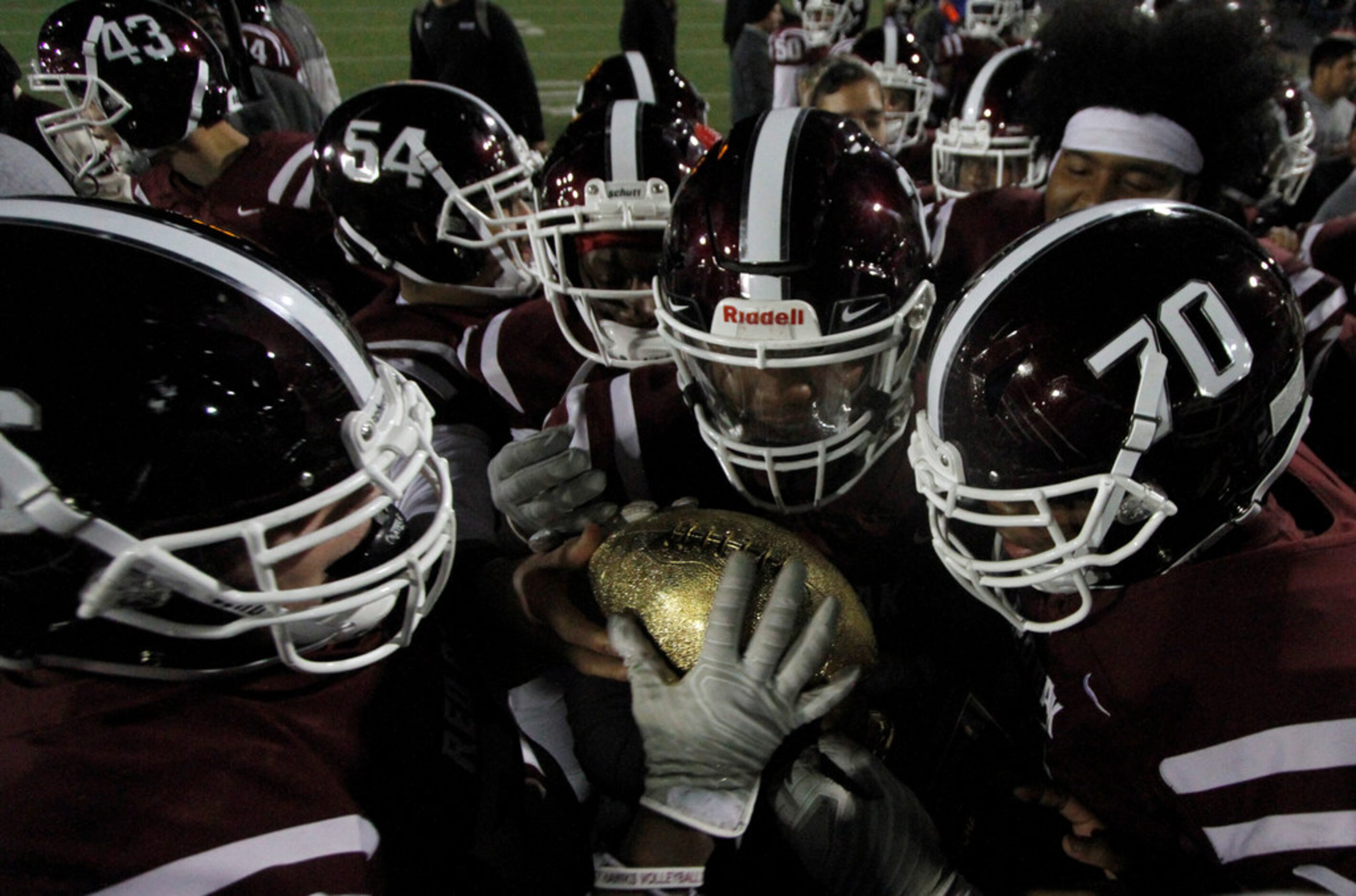 Members of the Red Oak Hawks marvel at the golden football atop a trophy presented after...