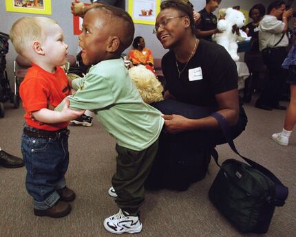 Ethan Housley (left), 16 months, gets a hug from K.L. Norwood, 2, with the help from his...