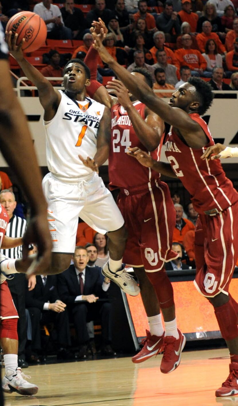 Oklahoma guard Buddy Hield, center, and forward Dante Buford, right, try to block a shot by...