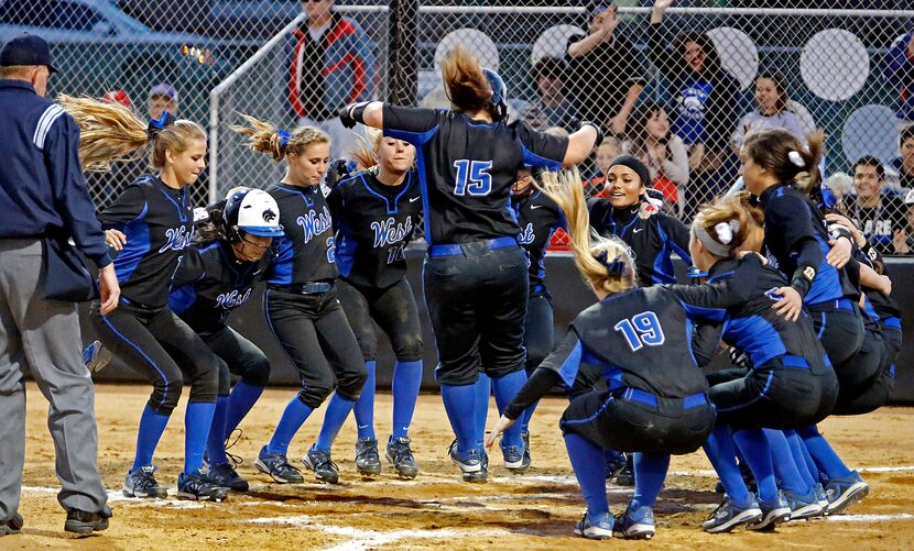 The Plano West High School varsity softball team rallys around catcher Margo Beck (15) at...