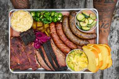 Kristopher Manning holds the Texas Trinity platter of brisket, ribs, jalapeño cheddar...