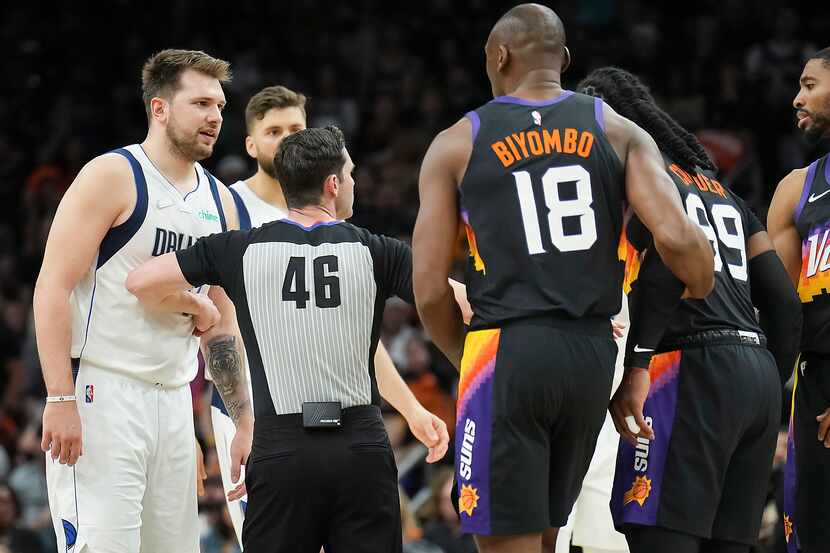 Referee Ben Taylor separates Dallas Mavericks guard Luka Doncic (77) from Phoenix Suns...
