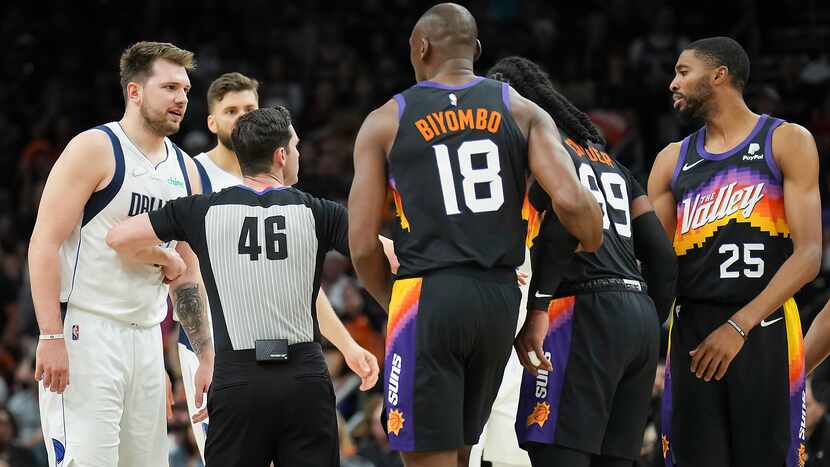 Referee Ben Taylor separates Dallas Mavericks guard Luka Doncic (77) from Phoenix Suns...