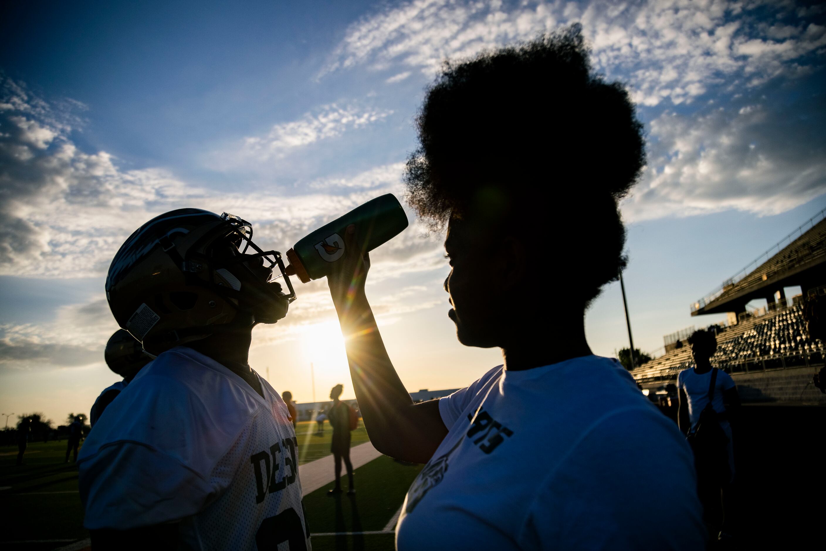 DeSoto freshman Darnesha Butler (right) gives a football player water during the first...