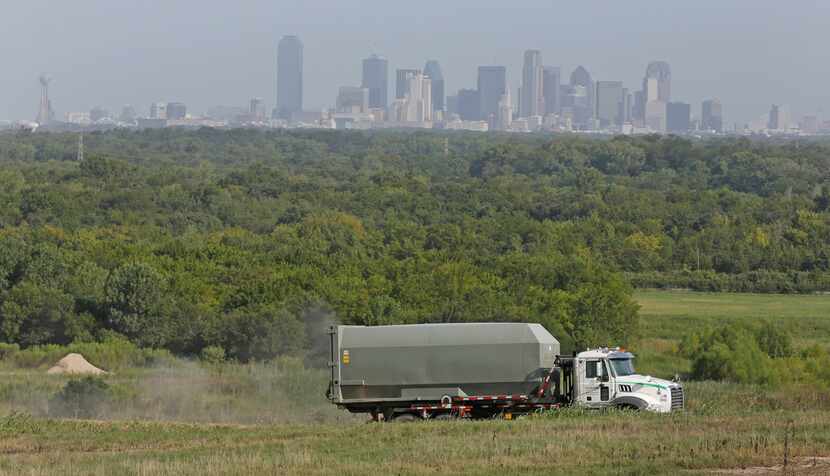 With the downtown Dallas skyline in the background, a trucks makes its way along the road in...