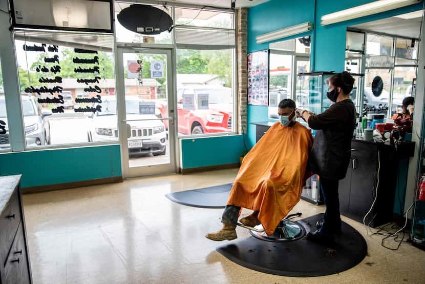A young man gets a haircut at a barbershop in Austin on May 8, following the slow reopening...