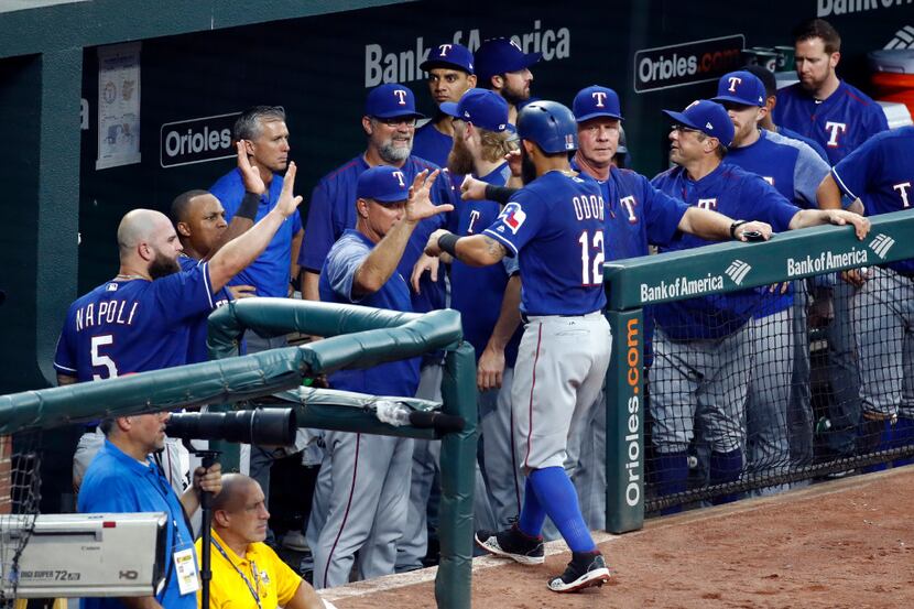 Texas Rangers' Rougned Odor (12) high-fives teammates in the dugout after scoring on Carlos...