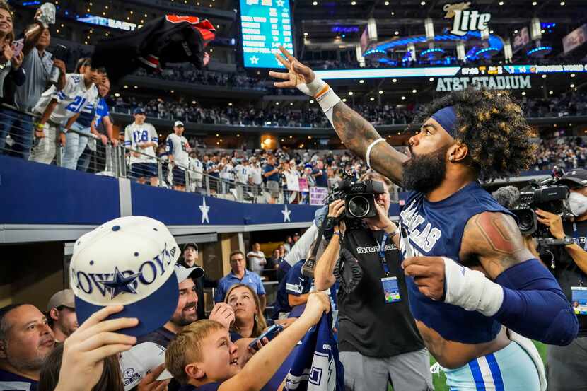 Dallas Cowboys running back Ezekiel Elliott tosses a jersey back to a fan after autographing...