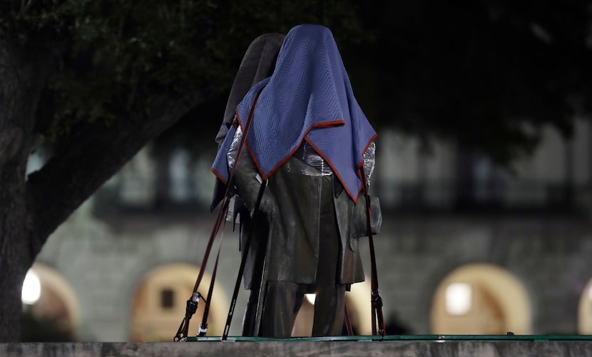 Confederate statutes removed from the University of Texas were covered and secured to a...