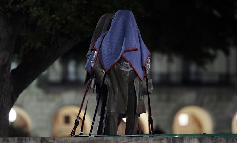 Confederate statutes removed from the University of Texas were covered and secured to a...