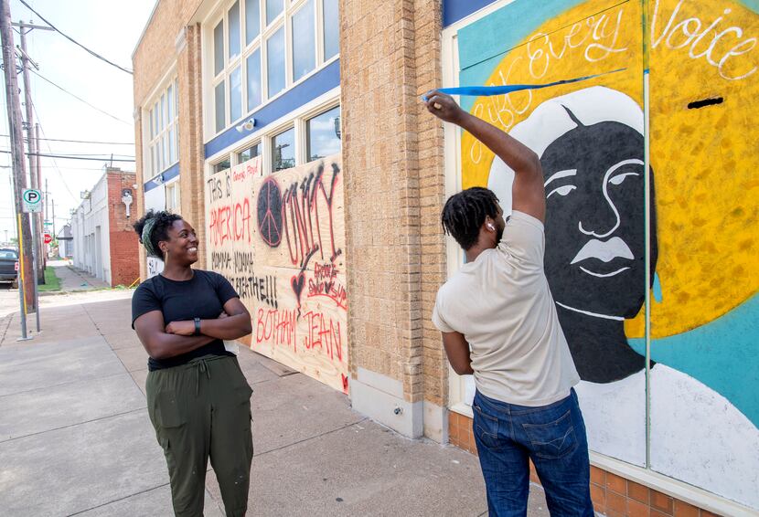 Desiree Vaniecia (left) watches as Joeneal Berry pulls masking tape off of a mural they...
