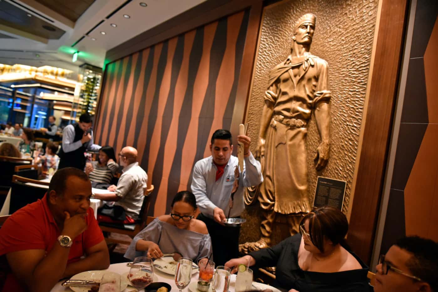 A brass gaucho is on display inside the main dinning hall as Eduardo Rodriguez serves meat...