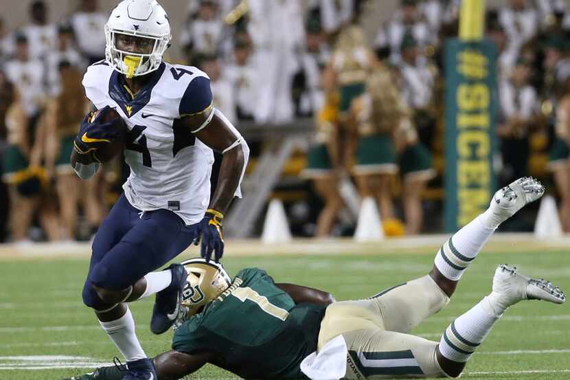 West Virginia running back Kennedy McKoy (4) runs past Baylor linebacker Taylor Young (1) in...