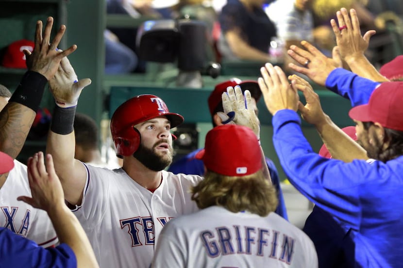 Texas Rangers first baseman Mitch Moreland is congratulated by teammates in the dugout after...