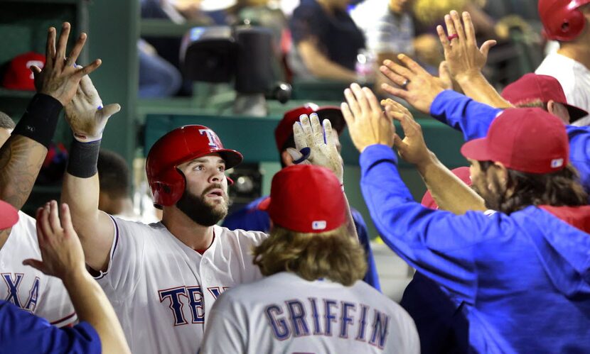 Texas Rangers first baseman Mitch Moreland is congratulated by teammates in the dugout after...