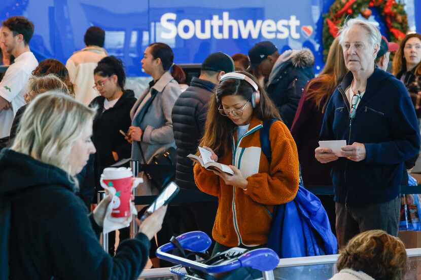 Ketmany Rasasack reads as she waits in line to reach a Southwest Airlines ticket counter at...