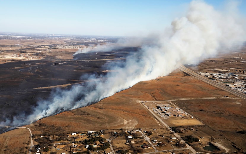 A grass fire churns across the landscape just north of I-20 (far right), near homes that...