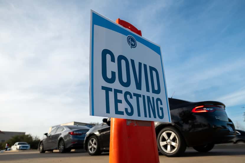 Signage is on display as motorists wait for a COVID-19 test in the parking lot of ...