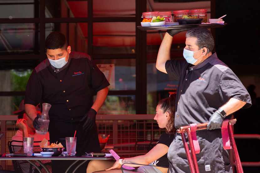 A server brings food out to the outside patio of Beto & Son at Trinity Groves on Friday in...