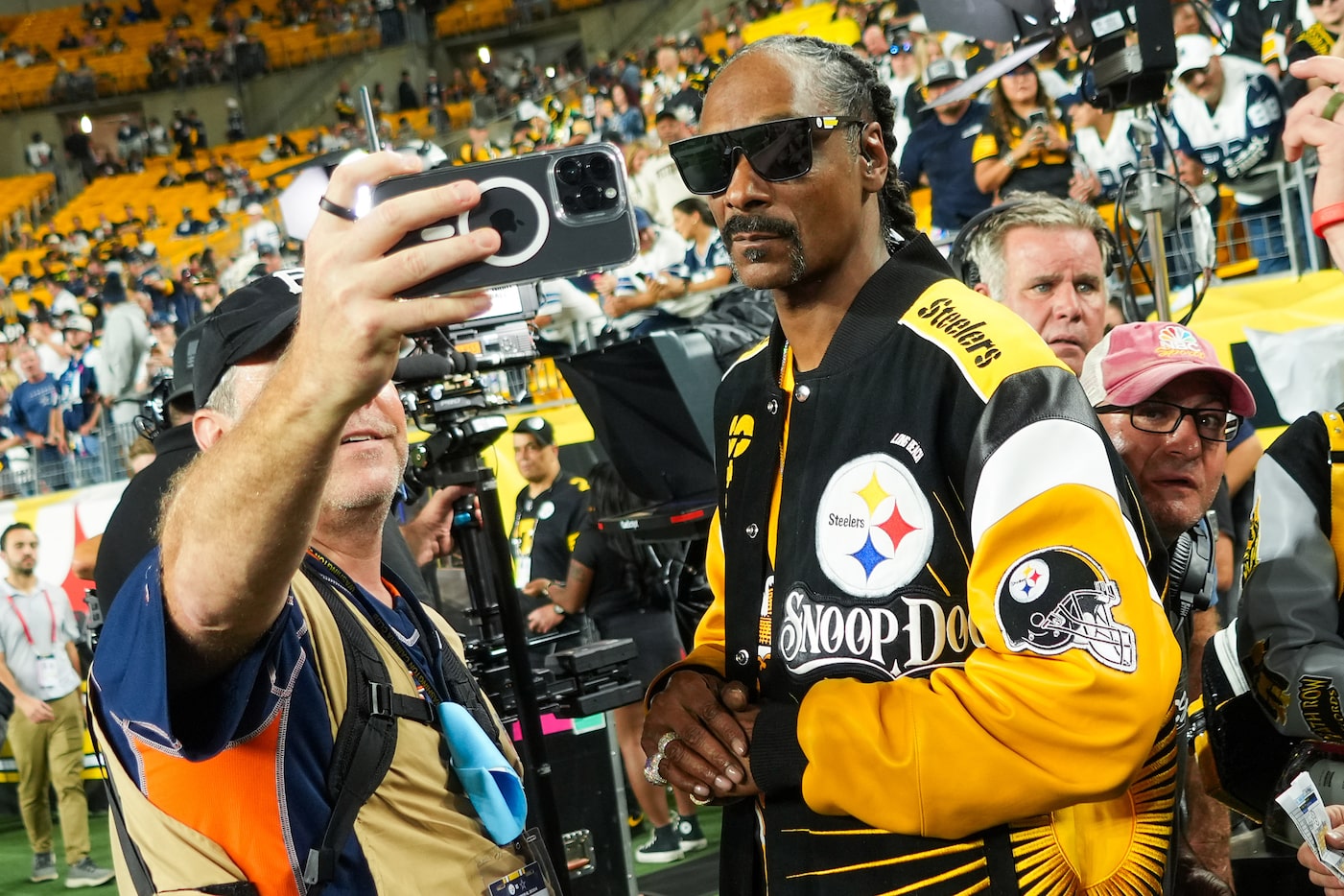 Rapper Snoop Dogg poses for photos on the field before an NFL football game between...