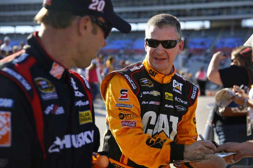 Sprint Cup Series driver Jeff Burton, center, signs autographs for fans with points leader...