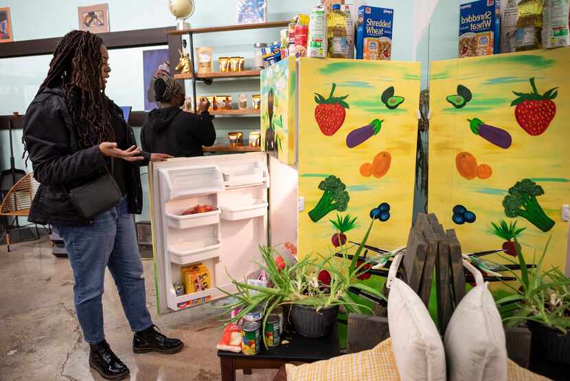Jasmine Coleman, left, looks in her free refrigerator concept titled The People's Fridge...