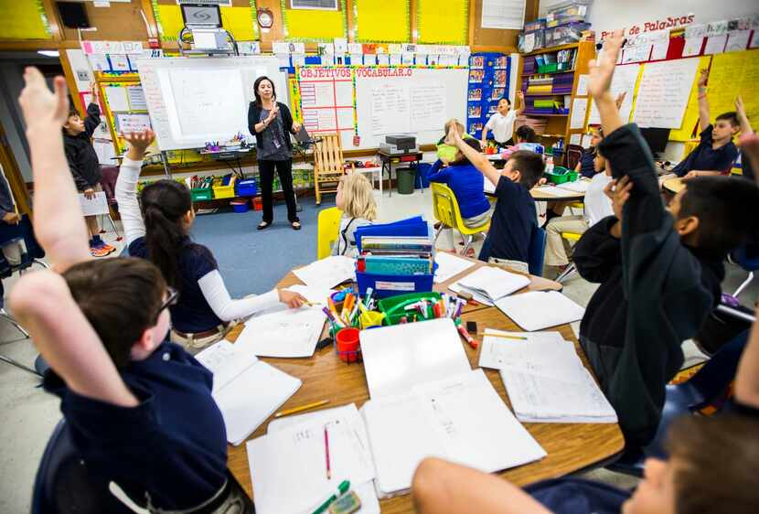 
Students raise their hands while third-grade teacher Irma De La Guardia teaches a science...