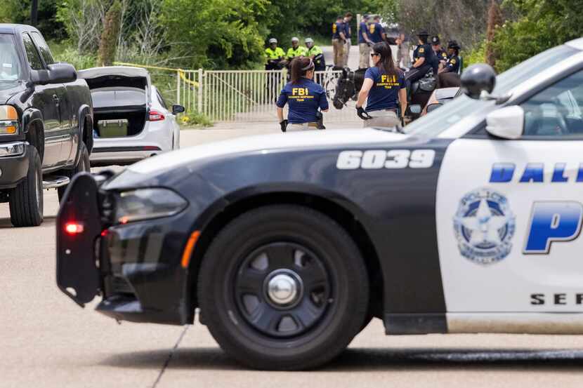 Dallas police and the FBI work the scene where a toddler boy was found dead early Saturday,...