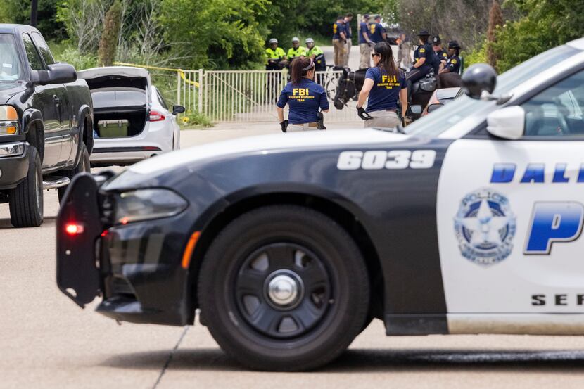 Dallas police and the FBI work the scene where a toddler boy was found dead early Saturday,...