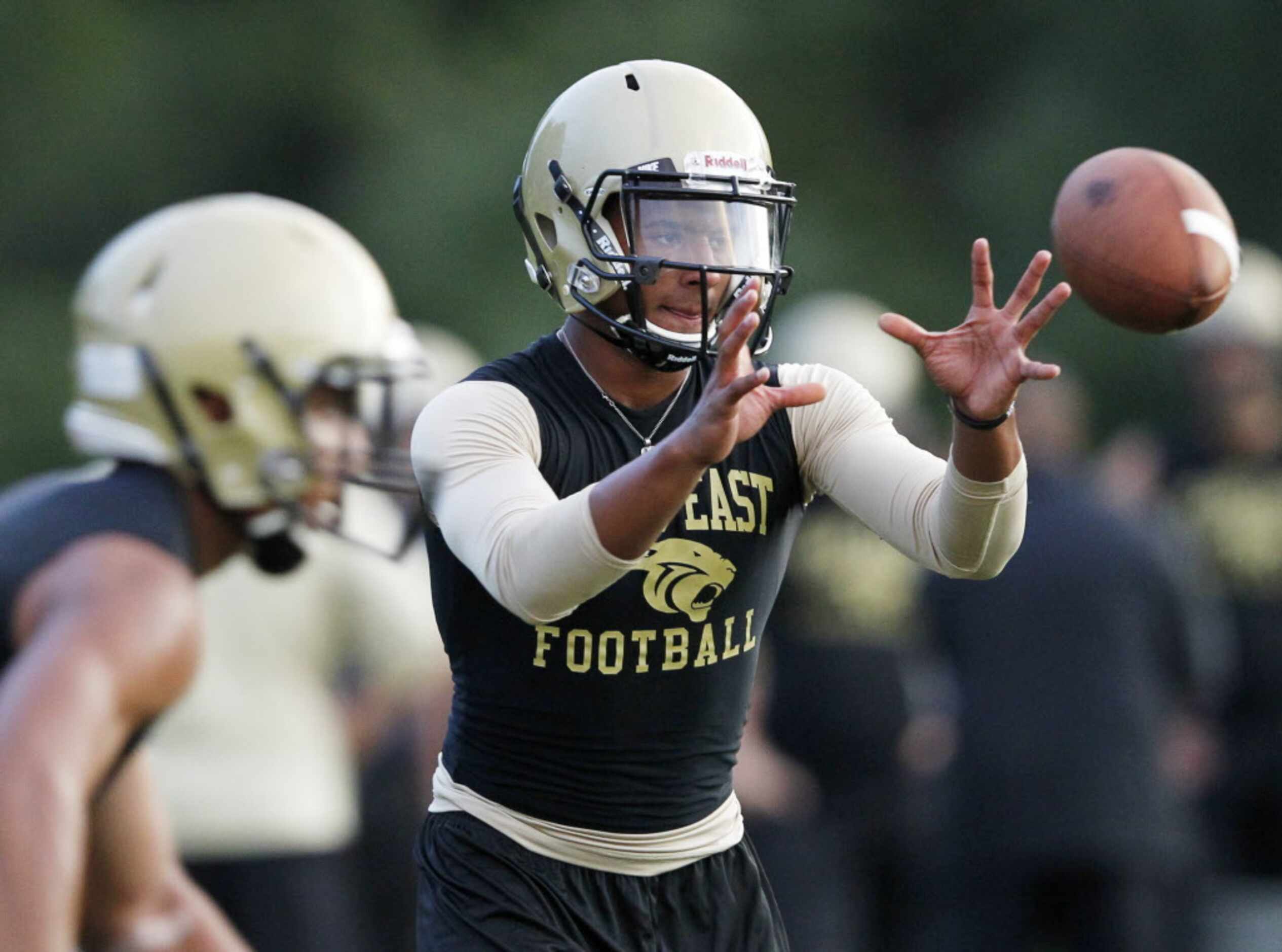 Plano East's quarterback Miles Thompson prepares to catch the ball at the start of a play...