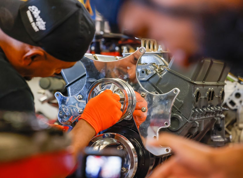 Mechanic Joél Balboa (left) works on the engine of a 1967 Chevy II Nova.