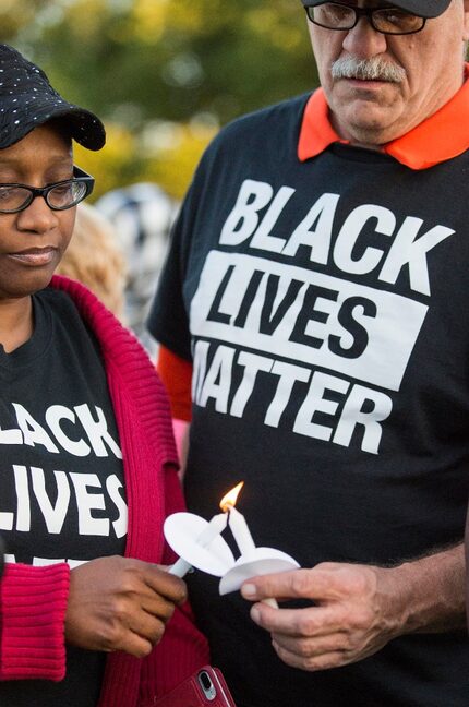 Monica Tunstle-Garrett (left) helps Al Woolum light a candle during a vigil for Jordan...