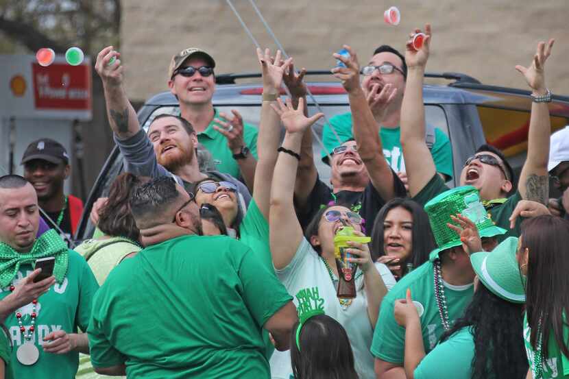 Spectators reach for Jello shots thrown in the crowd during the Dallas St. Patrick's Parade...