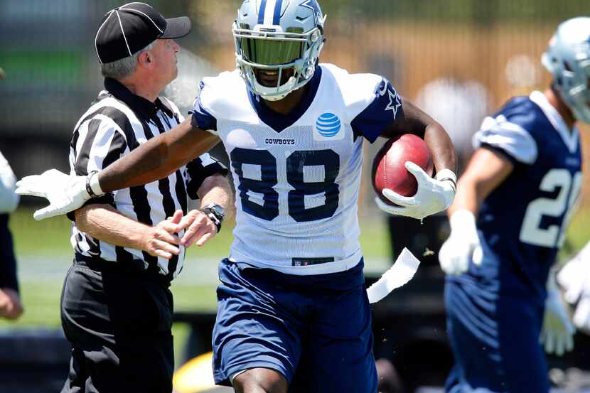 Dallas Cowboys wide receiver Dez Bryant (88) gave the official a stiff arm after making a...