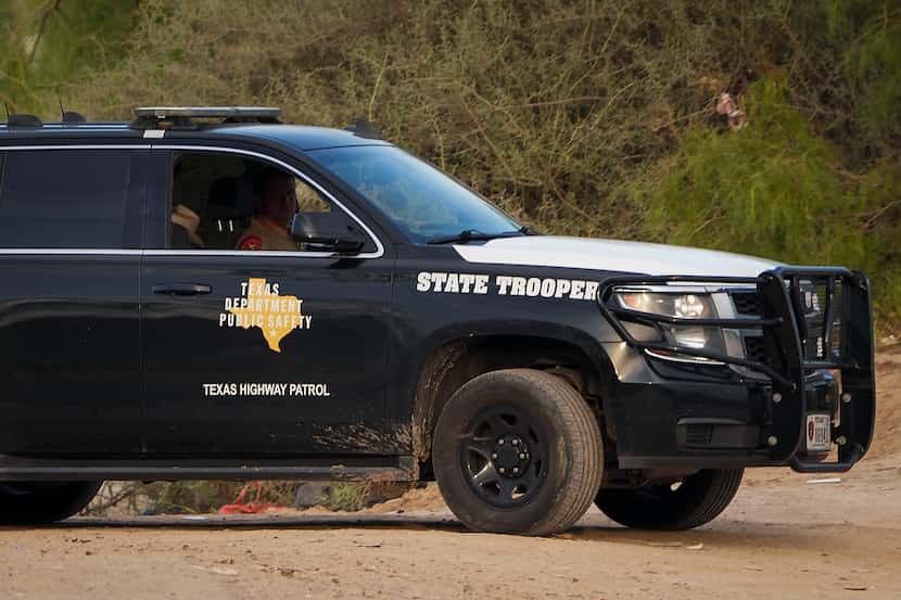 A Texas Department of Public Safety trooper watches over a group of migrants who turned...