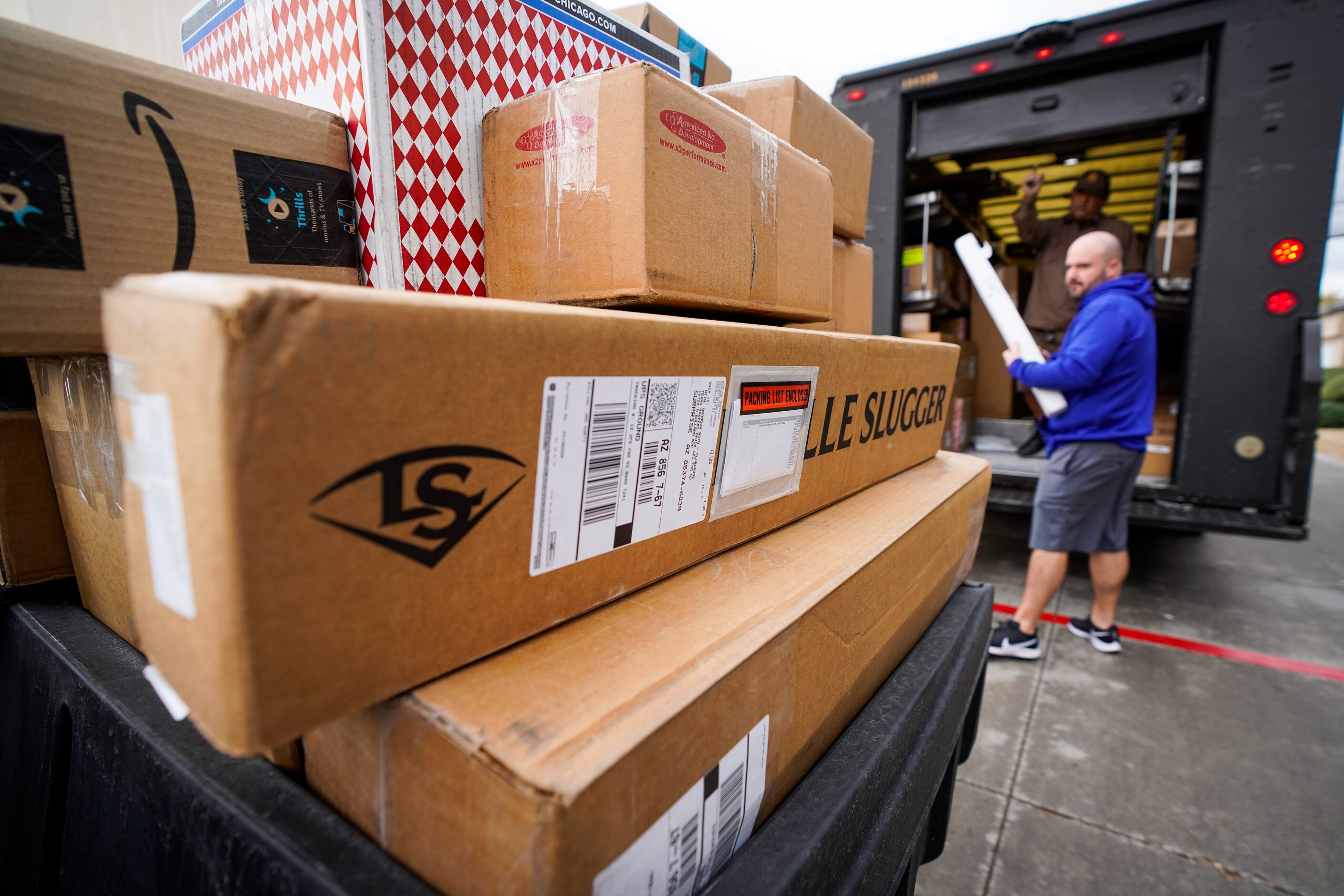 Boxes from a UPS delivers, including plenty of bats and other equipment, are loaded onto a...