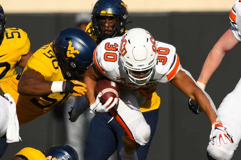West Virginia defensive end Jared Bartlett (50) reaches for Oklahoma State running back...
