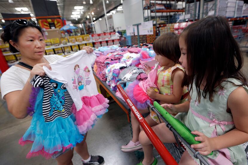 In this June 4, 2014 photo, Carry Johnson, left, shows dresses to her daughters Zoey, 3,...