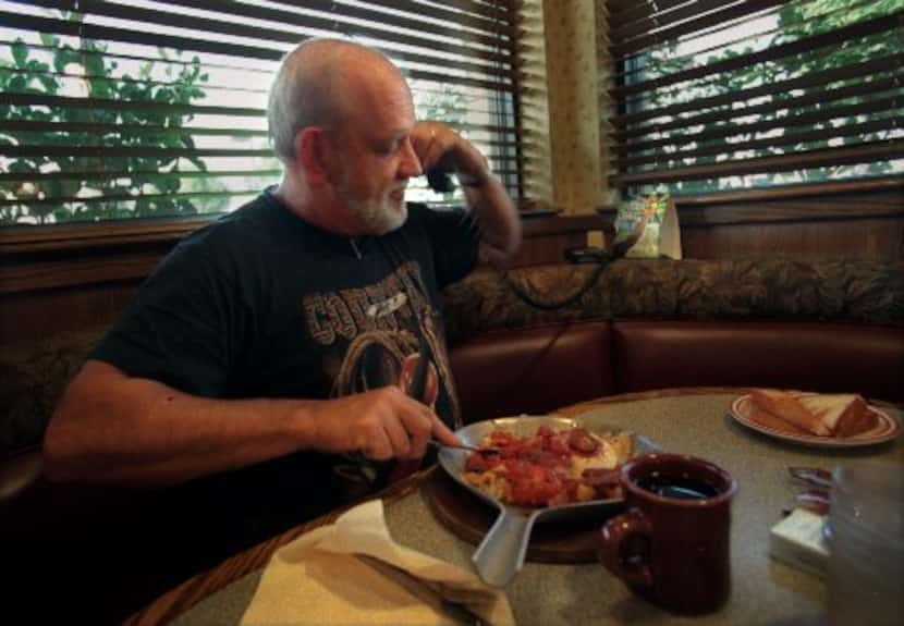 Trucker Joe '"Lucky" Moews eats  breakfast while talking on the telephone to his wife,...
