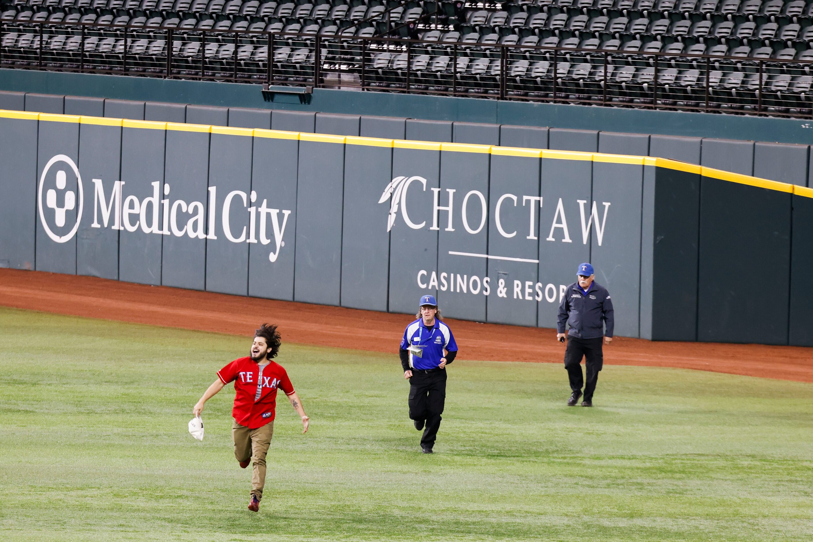 Security chases after a fan who ran onto the field following Texas Rangers’ winning the...