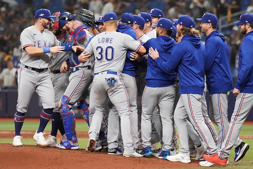 Texas Rangers players celebrate around catcher Jonah Heim after a victory over the Tampa Bay...