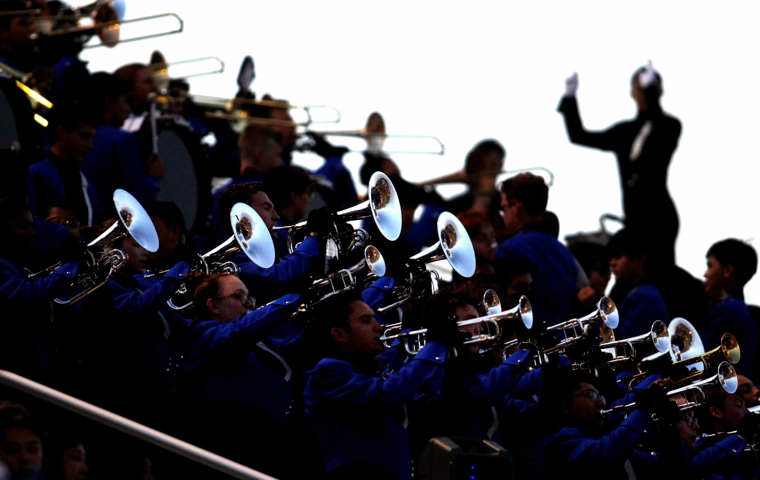 Members of the Hebron brass section shine as the band performs from the stands during first...
