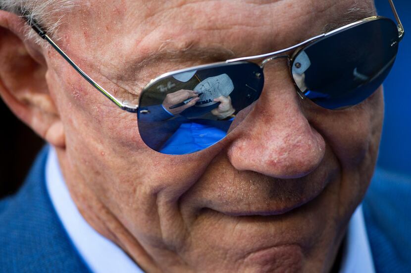 Dallas Cowboys owner Jerry Jones signs autographs for fans before an NFL football game...