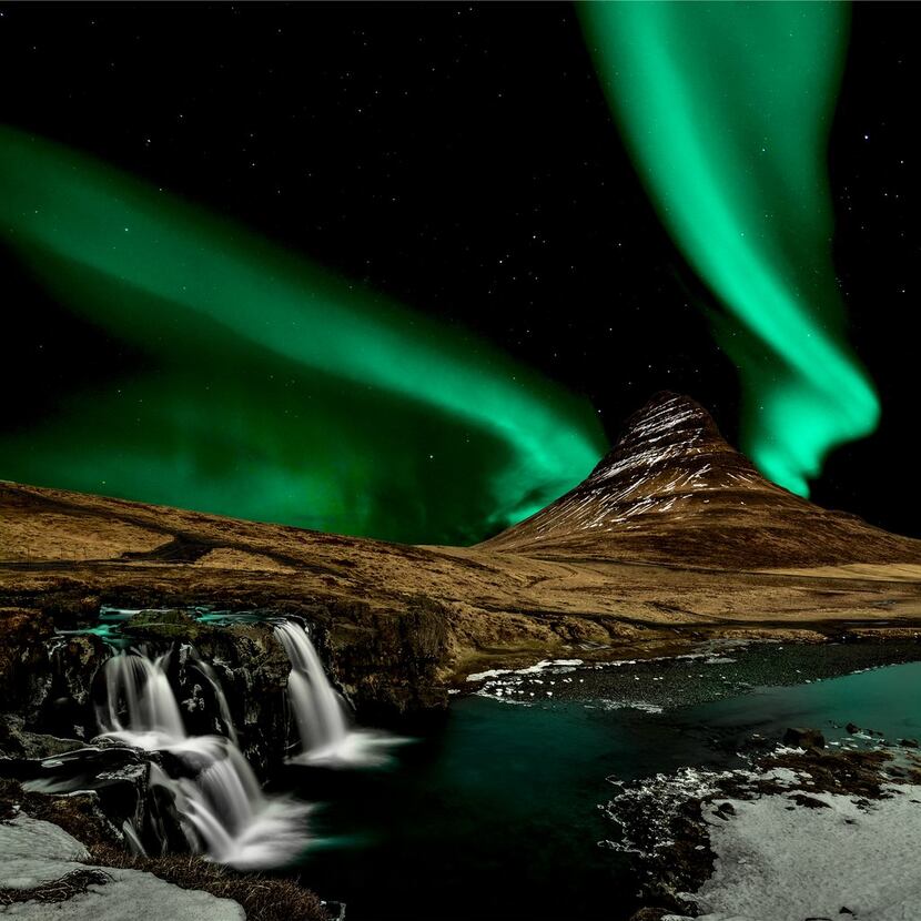 The northern lights illuminate the night sky over Iceland's impressive landscape in this...