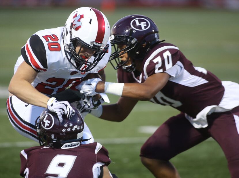 Flower Mound Marcusâ Alex Albright, cq, 20, is tackled by Lewisvilleâs DeâMondrick...