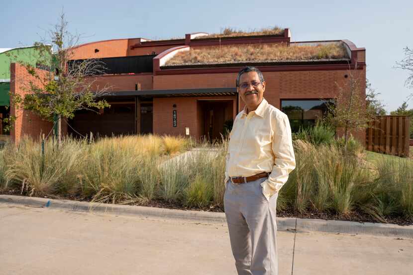 Total Environment Homes founder Kamal Sagar outside a model home with a grass-covered...