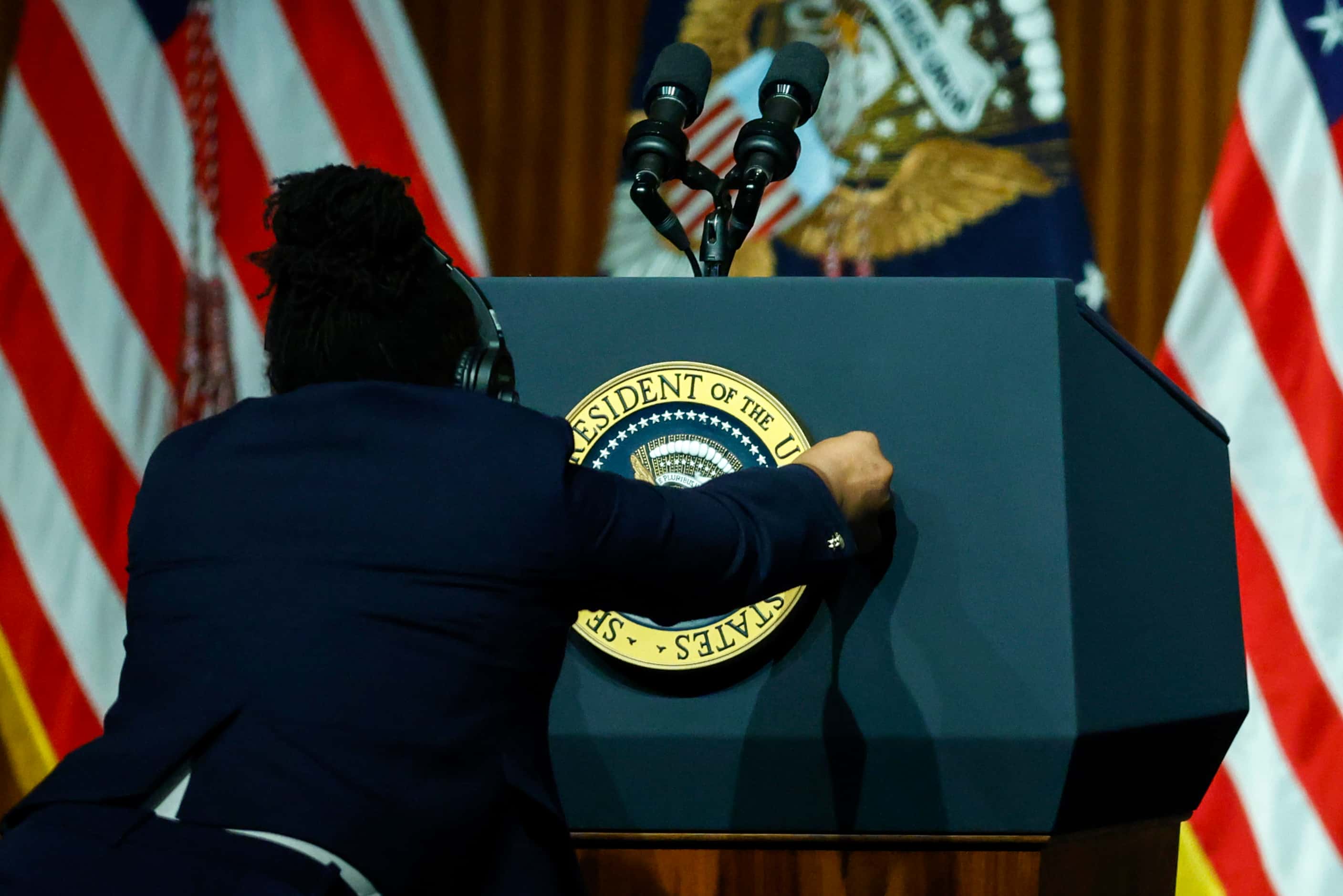 A staffer places the presidential seal on the podium before President Joe Biden delivers the...